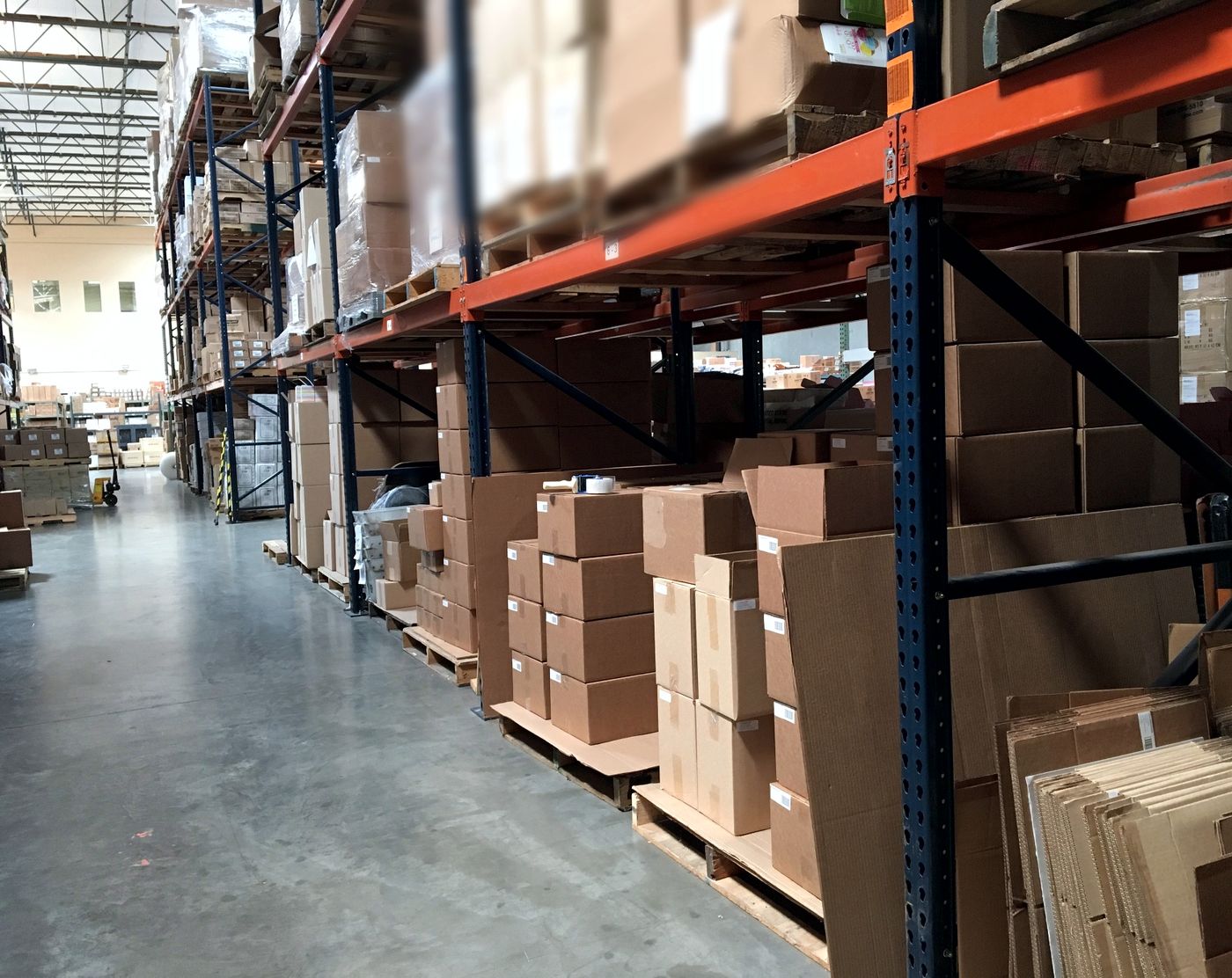 A pallet racking aisle inside the Minimus Fulfillment warehouse, stacked with cased inventory